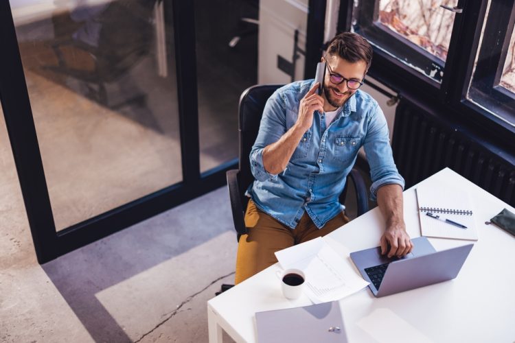 Smiling,Young,Man,Sitting,In,The,Office,By,The,Window