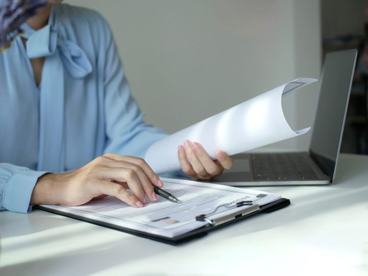 Asian,Businesswoman,Employer,Sitting,Holding,New,Employee's,Documents,To,Evaluate